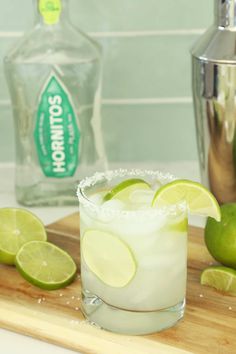 a close up of a margarita on a cutting board with limes