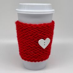 a knitted cup cozying with a button on the side and a coffee cup sleeve