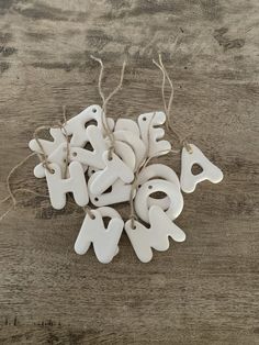 white ceramic letters and numbers hanging from twine on wooden table with string attached to strings