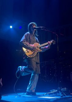 a man standing on top of a stage holding a guitar