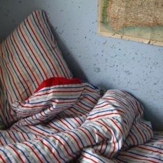 an unmade bed with red, white and blue striped sheets on top of it