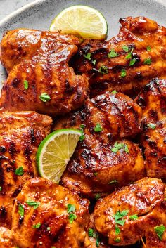 chicken with lemon and cilantro on a plate next to a lime wedges