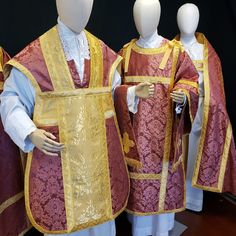 three mannequins dressed in red and yellow robes with gold trimmings