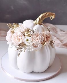 a white pumpkin decorated with flowers and gold leafy decorations on top of a plate