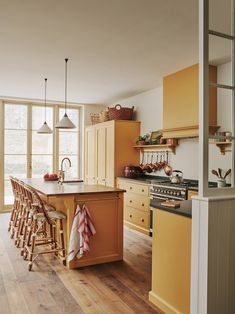 a kitchen with yellow cabinets and wooden floors