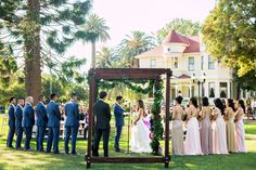 a group of people standing in front of a wedding ceremony on top of a lush green field