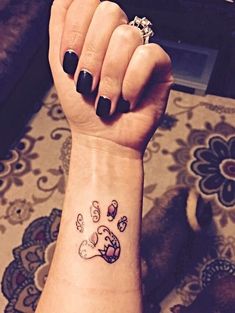 a woman's wrist with a dog paw tattoo on it