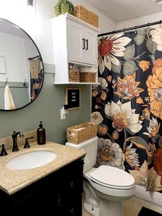 a bathroom with a floral shower curtain next to a white toilet and black vanity sink