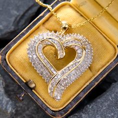 This radiant pendant features ninety-five baguette diamonds and fifty-four round brilliant cut diamonds arranged in the shape of an ornate heart with a bypass at the base. The pendant is crafted in 10k yellow and white gold and comes with a 14k yellow gold 18 inch long cable chain with small jump rings so it can also be worn at 16 and 17 inches. Antique Engagement Rings Sapphire, Estate Jewelry Rings, Wedding Ring Diamond Band, Diamond Heart Pendant Necklace, Baguette Diamonds, Heart Diamond, Heart Pendant Diamond, Baguette Cut Diamond, Antique Engagement Rings