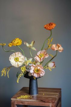 an arrangement of flowers in a black vase on a table