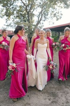 a group of women in pink dresses standing next to each other on a dirt field