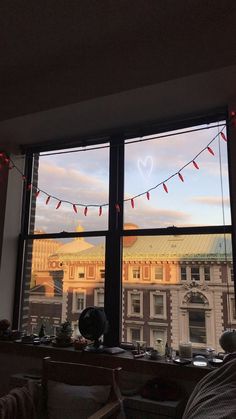 a window with string lights hanging from it's sides and a view of the city outside