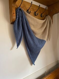 a wooden coat rack with two coats hanging from it's sides and three hooks on the wall