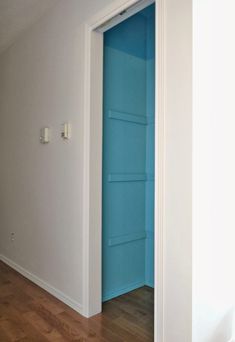 an empty room with a blue door and hard wood floor