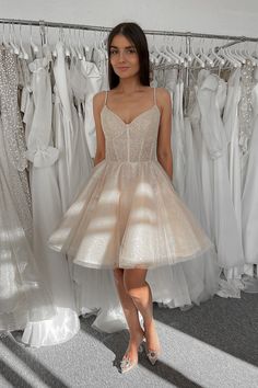 a woman standing in front of some dresses