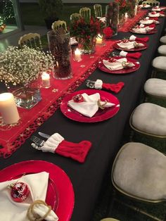 a long table is set with red and white plates, napkins, candles and flowers