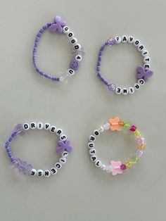 four bracelets with name beads on them sitting next to each other and one has a butterfly