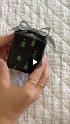 a person holding a black present with green trees on it