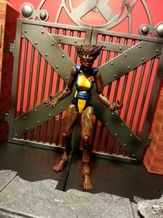 an action figure standing in front of a gate