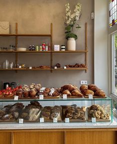 a display case filled with lots of different types of bread and pastries in front of a window