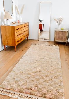 a room with a rug, dresser and mirror