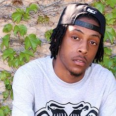 a young man with dreadlocks sitting in front of a wall