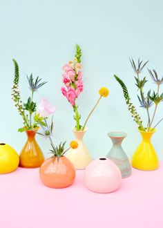 a group of vases with flowers in them on a pink tablecloth against a blue wall