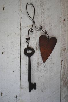 an old key with a heart hanging from it's side on a white wooden background