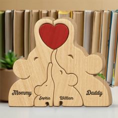 two wooden elephants holding a heart with the words mommy, son and daughter engraved on them