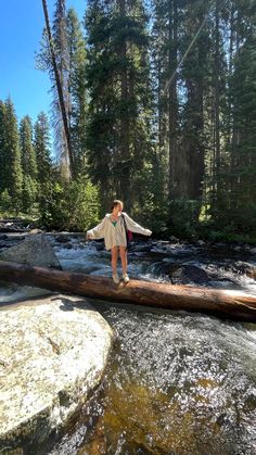 a man standing on a log over a river