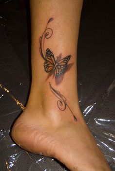 a butterfly tattoo on the foot of a woman's leg, with swirls and leaves