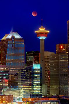 the city skyline is lit up at night with bright lights and skyscrapers in the background