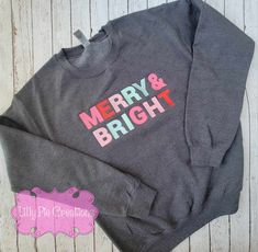 This Merry & Bright Sweatshirt will be the envy of all your festive friends. It's colorful, trendsetting and perfect for your Christmas wardrobe. Available in pink, grey or blue, this stylish sweatshirt is sure to bring some seasonal cheer! All of my items are made to order, if you have any questions please don't hesitate to ask! Festive Cotton Tops For Fall, Winter Fun Relaxed Fit Tops, Fun Winter Tops With Relaxed Fit, Festive Holiday Cotton Sweater, Fun Cotton Sweatshirt For Winter, Christmas Wardrobe, Baby Applique, Fun Christmas Activities, Cocoa Christmas