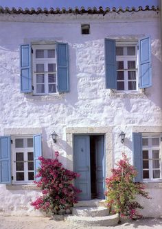 a white house with blue shutters and flowers