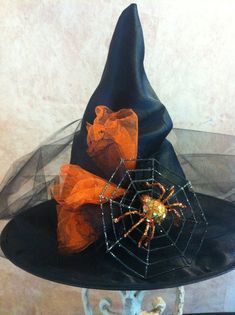 a witches hat with spider web and orange sequins sits on top of a table