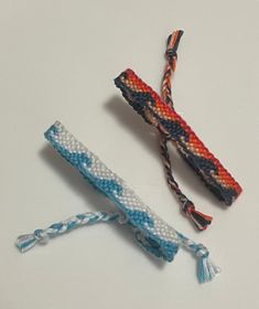 there are two different types of bracelets on the white table and one is blue, orange, and white