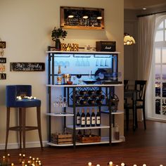 a bar with wine bottles and glasses on it in front of a window that is lit up