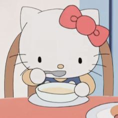 a hello kitty sitting at a table eating food