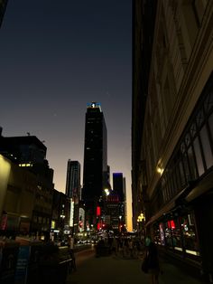 a city street at night with tall buildings in the background