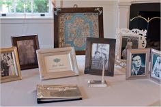 a table topped with pictures and frames on top of a white cloth covered tablecloth