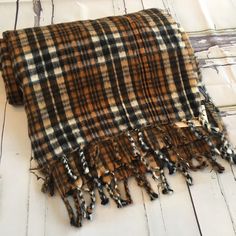 a brown and black plaid blanket laying on top of a white wooden floor next to a wall