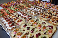 an assortment of appetizers are displayed on a table with other food items in the background