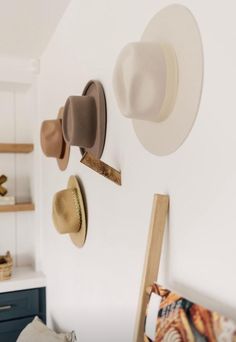 several hats are hanging on the wall above a bed in a room with white walls