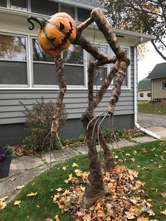 a fake spider with a pumpkin on it's head in front of a house