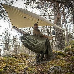 a man is holding a hammock in the woods