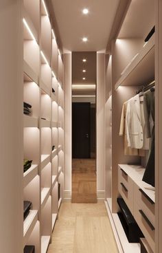 a walk - in closet with white shelving and wooden flooring is lit by recessed lighting