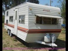 an rv is parked in the grass next to a fire hydrant and water tank