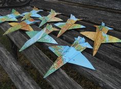 several origami airplanes are sitting on a park bench with maps pinned to them