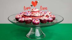 cupcakes are arranged on a glass plate with the word love spelled in red