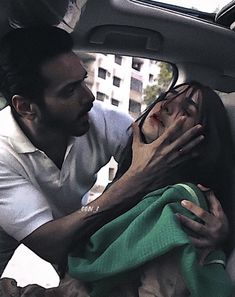 a man and woman in the back of a car with their hands on each other's chest